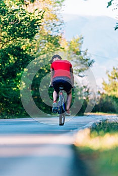 Fit cyclist rides his bicycle bike on an empty road in nature