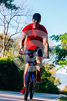 Fit cyclist rides his bicycle bike on an empty road in nature