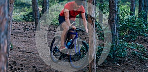 Fit cyclist riding his bike downhill through a forest  woods  while wearing a red shirt and red shoes