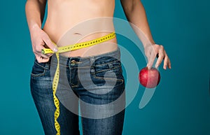 Fit female body with apple and measuring tape. Healthy fitness and eating, diet lifestyle concept.