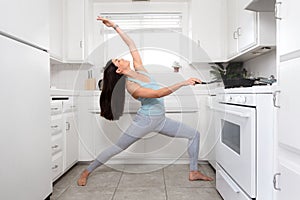 Fit female cooking and exercising at the same time, funny lifestyle advertisement, yoga pose in tiny home