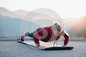 Fit female doing intense core workout. Adult woman doing push up exercise on fitness mat