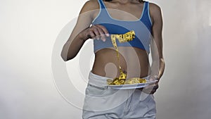 Fit female rolling measure tape around fork, healthy weight loss, nutrition
