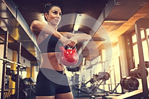 Female use kettle bell weight for exercising muscles photo