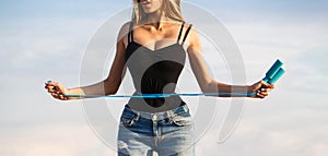 Fit fitness girl measuring her waistline with measure tape. Athletic slim woman measuring her waist by measure tape photo