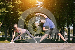 Fit fitness woman and man doing stretching exercises outdoors at park