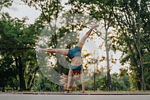 Fit and flexible athletic girl performing impressive 360 degree cartwheels in a green park. She shows strength and