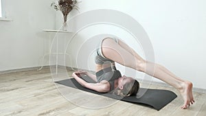 Fit flexible female in sportswear raises legs up, bends back. yoga, stretching