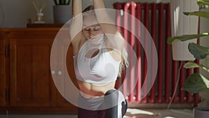 Fit, flexible long hair blond caucasian female doing yoga poses and head stand at home. Front view 4k video footage