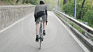 Fit focused cyclist pedaling bicycle out of the saddle uphill. Strong legs with muscles pedaling. Uphill training for a cycling ra