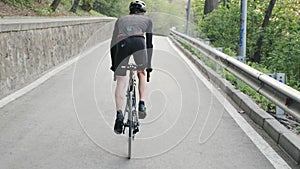 Fit focused cyclist pedaling bicycle out of the saddle uphill. Strong legs with muscles pedaling. Uphill training for a cycling ra