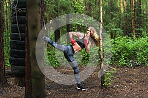 Fit girl beat high leg side kick working out outdoors. Woman fighter exercising, doing kickboxing training martial arts