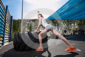 Fit girl with giant truck workout turning tire over.