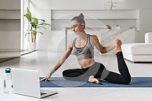 Fit girl has a virtual yoga class on laptop