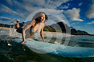 Fit girl having fun starting to surf in ocean water