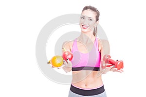 Fit girl holding fruits and weights as balance