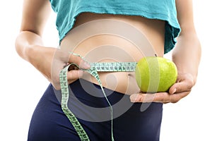 Fit girl measuring her waist and holding green apple