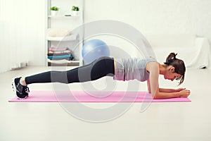 Fit girl in plank position on mat at home the living room exercise for back spine and posture Concept pilates fitness