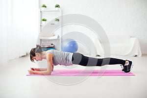 Fit girl in plank position on mat at home the living room exercise for back spine and posture Concept pilates fitness