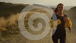 Fit girl running marathon in mountain landscape. Tired jogger stopping after run