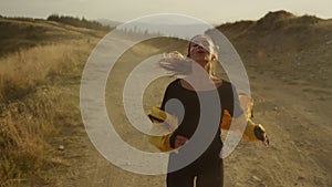 Fit girl running marathon in mountain landscape. Tired jogger stopping after run