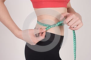 Fit girl takes her waist with a measurement tape