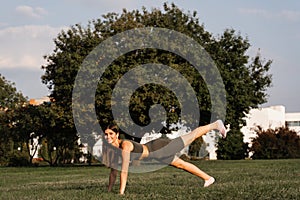 Fit girl training on green grass in the park. Outdoor workout. Sport lifestyle of active young woman.