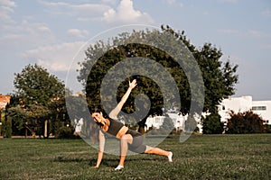 Fit girl training on green grass in the park. Outdoor workout. Sport lifestyle of active young woman.