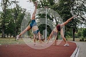 Fit girls inspire with evening training in nature. They perform 360-degree cartwheels and flips, displaying athleticism