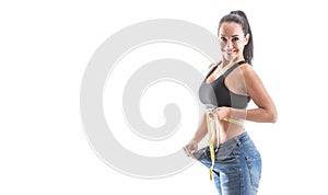 Fit good-looking woman shows great weight loss by loose jeans wearing sports bra on an isolated white background