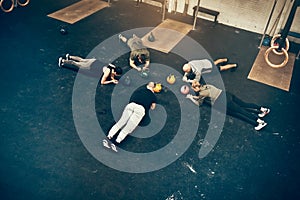 Fit group of people planking together on a gym floor photo