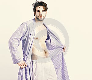 Fit guy with torso and six packs in blue bathrobe. Man with beard in blue dressing gown on white background.