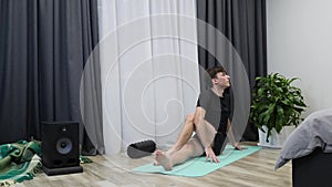 Fit handsome man stretches body muscles. Male athlete in activewear stretching on yoga mat. Young boy does aerobic and fitness exe