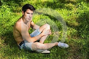 Fit handsome young man relaxing lying on lawn