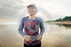 Fit and happy middle aged woman running on the beach - 40s or 50s attractive mature lady with grey hair doing jogging workout