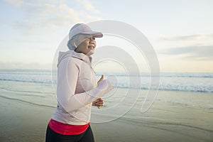 Fit and happy middle aged woman running on the beach - 40s or 50s attractive mature lady with grey hair doing jogging workout