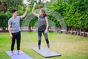 Fit happy people working out outdoor. Asian couple exercising together on a yoga mat at home garden. Family outdoors. exercise at