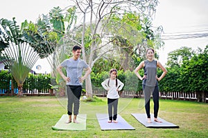 Fit happy people working out outdoor. Family Asian parent and child daughter exercising together on a yoga mat at home garden.