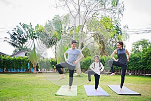 Fit happy people working out outdoor. Family Asian parent and child daughter exercising together on a yoga mat at home garden.