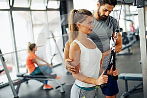 Fit happy woman with her personal fitness trainer in the gym exercising with dumbbells