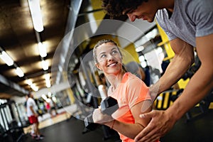 Fit happy woman with her personal fitness trainer in the gym exercising with dumbbells