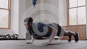 Fit and healthy black male at an indoor fitness gym. Focussed, and preparing for push up exercise.