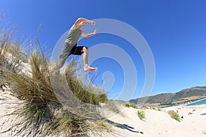   salutare medio vecchio uomo saltando Attraverso sabbia duna 