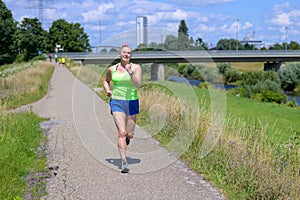 Fit healthy overweight woman jogging alongside a river