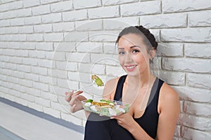Fit healthy woman in sportswear eating a fresh salad after fitness workout.