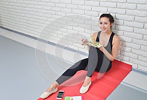 Fit healthy woman in sportswear eating a fresh salad after fitness workout.