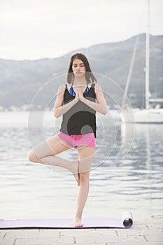 Fit healthy woman stretching on yoga mat on beach seaside,doing exercise abdominal crunches,training and lifestyle.