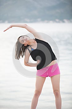 Fit healthy woman stretching on yoga mat on beach seaside,doing exercise abdominal crunches,training and lifestyle.