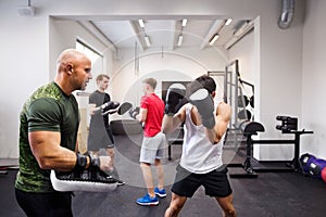 Fit hispanic man in gym boxing with his trainer.