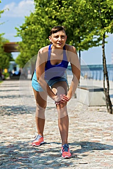 Fit jogger woman resting after run in city park.